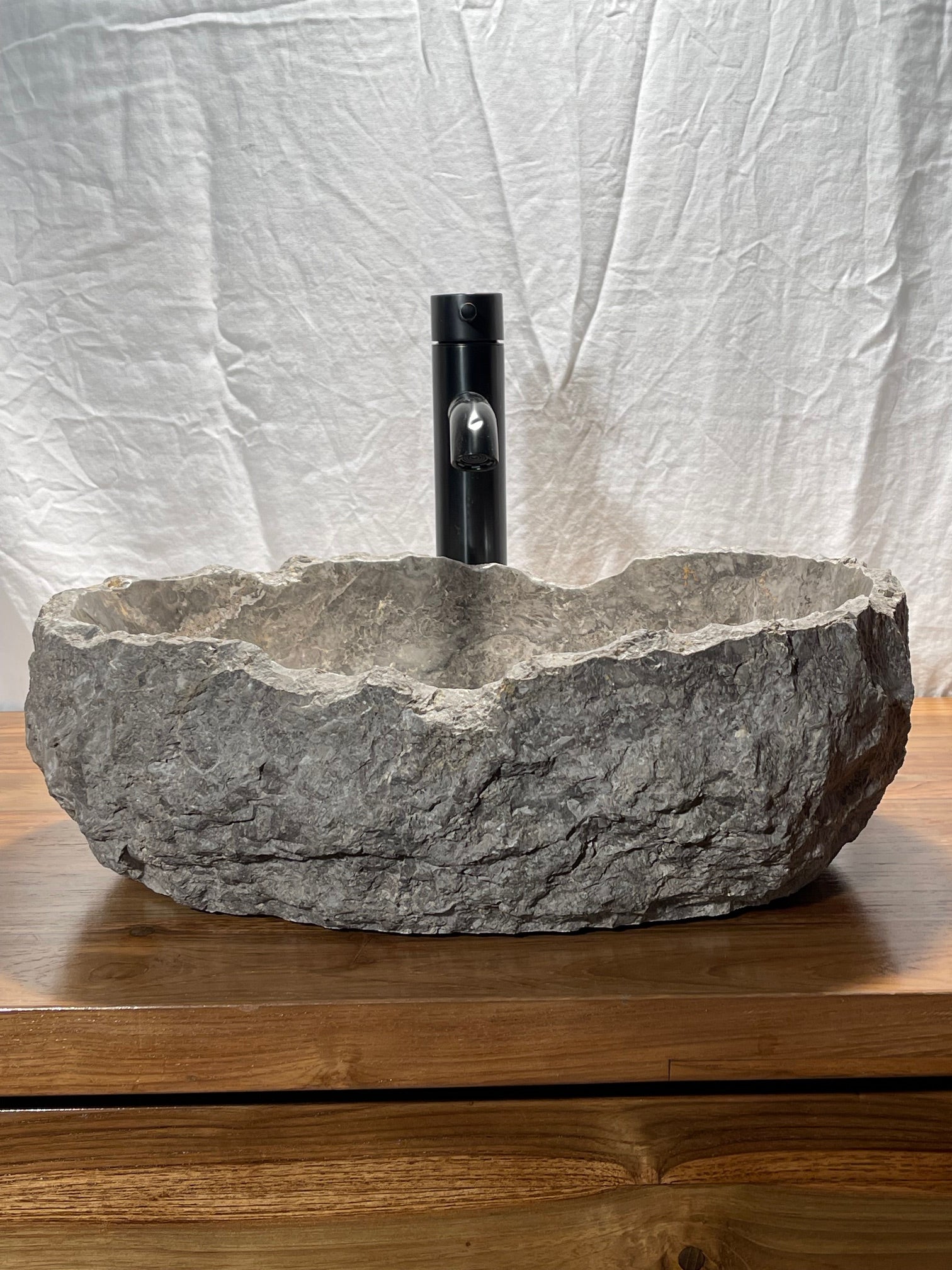 Gray marble vessel sink with naturally organic bowl lip and chiseled exterior at Impact Imports