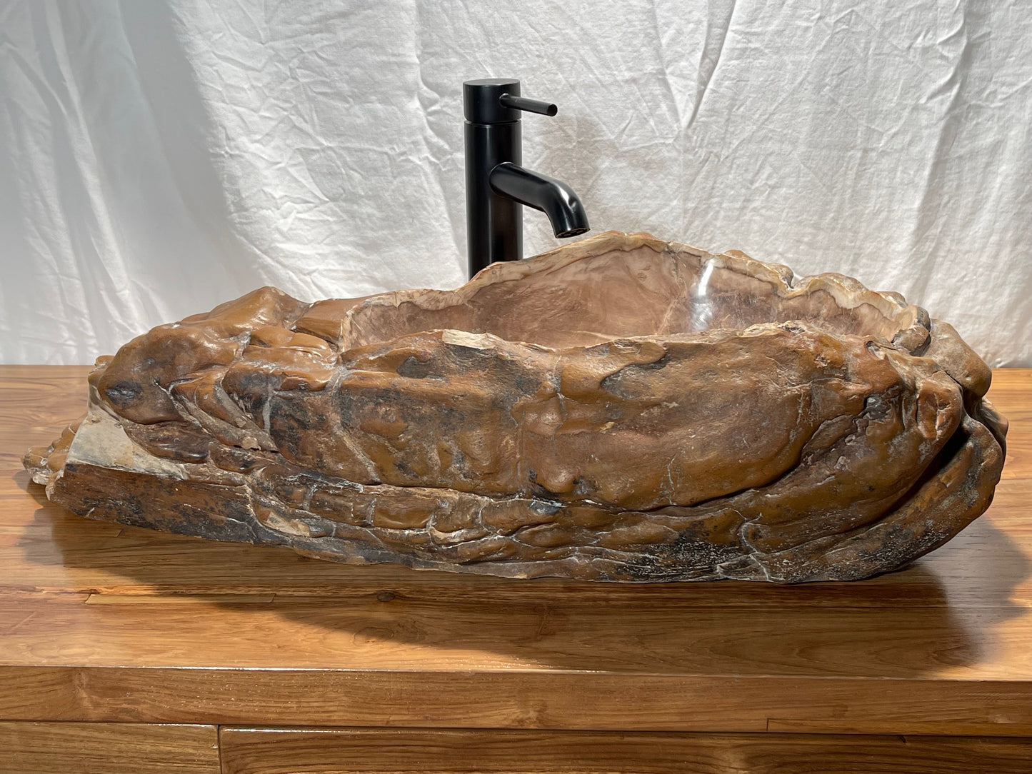 Log shaped petrified wood stone vessel sink with a textured but smooth brown exterior color at impact imports of Boise, Idaho