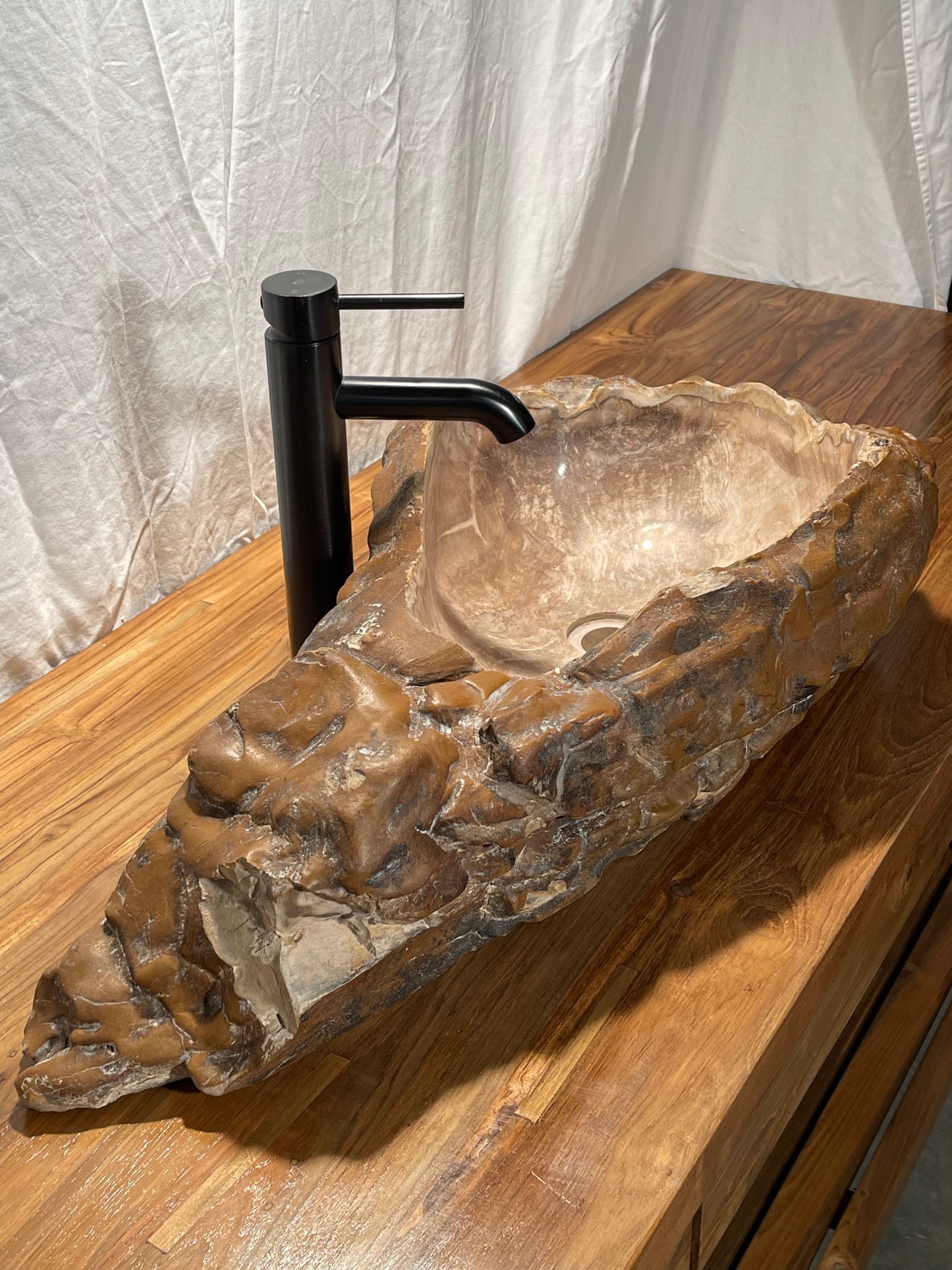 Log shaped petrified wood stone vessel sink with a textured but smooth brown exterior color at impact imports of Boise, Idaho