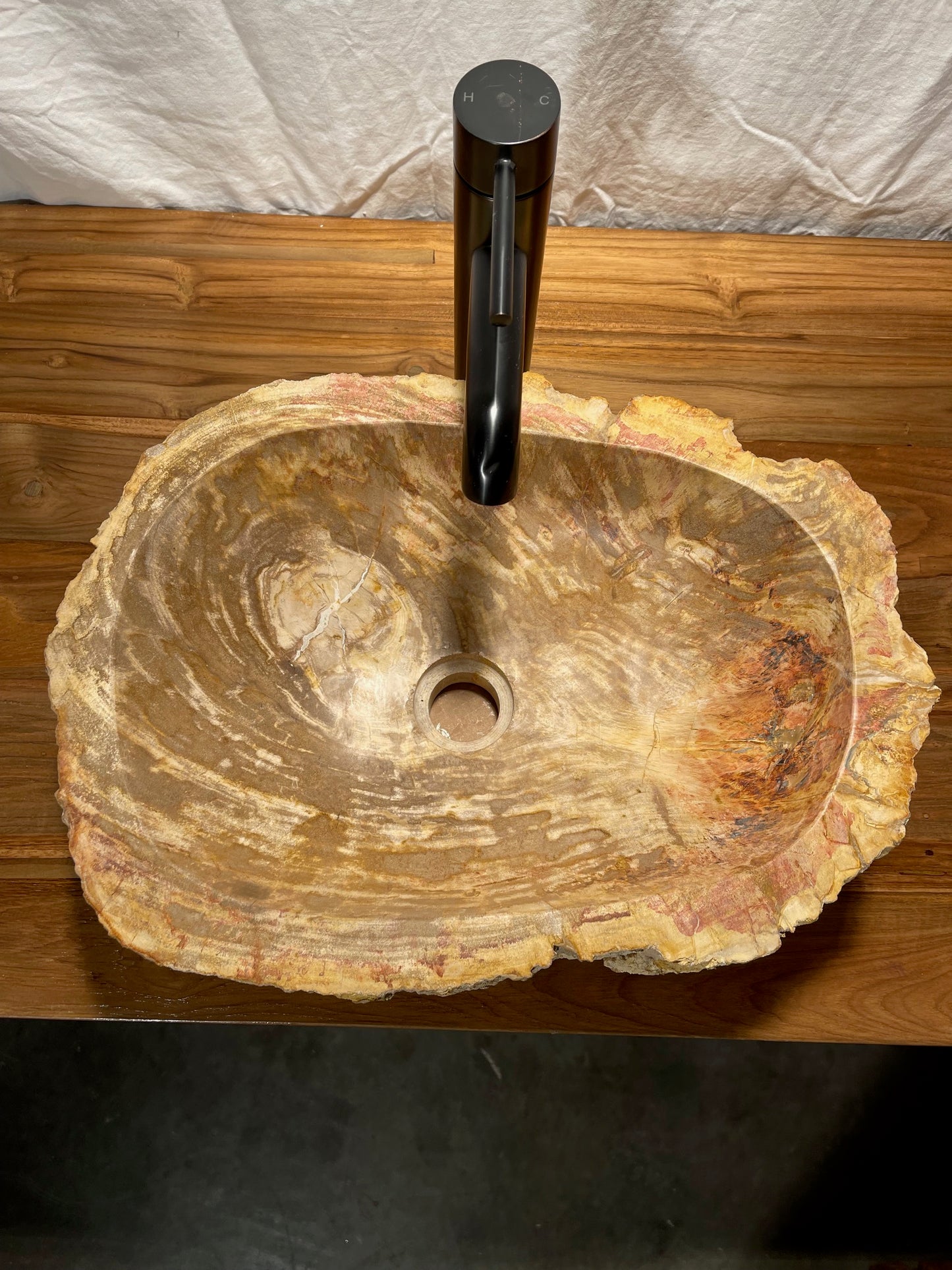 Log shaped petrified wood stone vessel sink with a textured but smooth brown exterior color at impact imports of Boise, Idaho