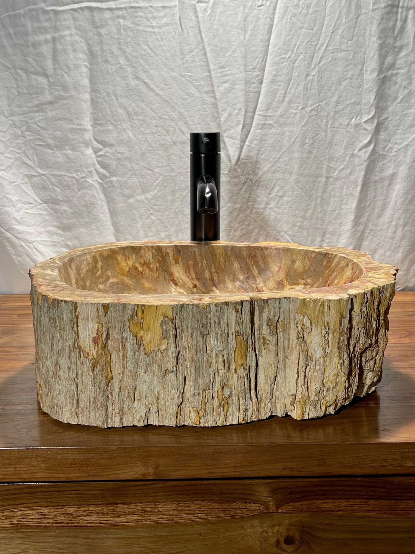 Log shaped petrified wood stone vessel sink with a textured but smooth brown exterior color at impact imports of Boise, Idaho