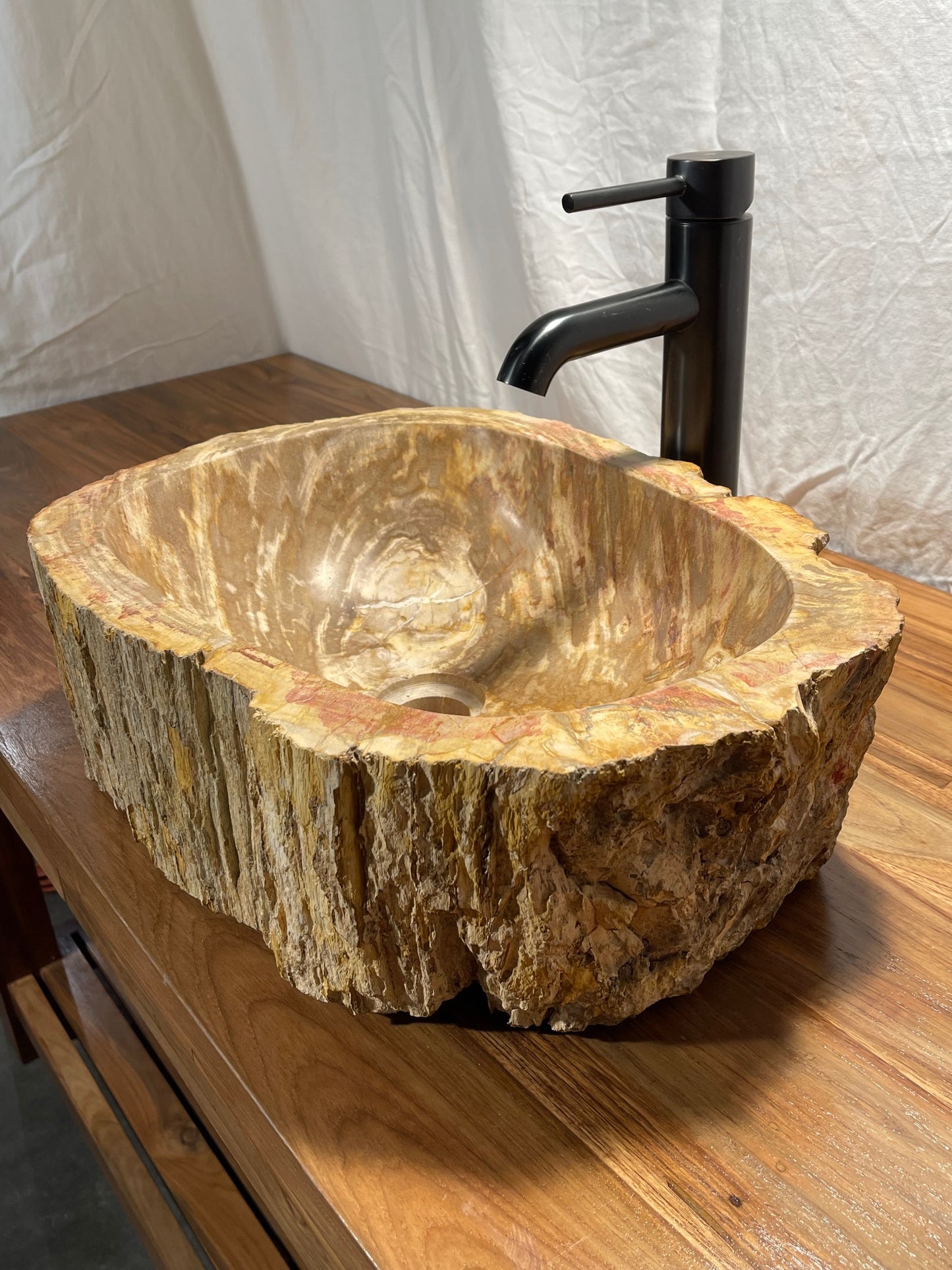 Log shaped petrified wood stone vessel sink with a textured but smooth brown exterior color at impact imports of Boise, Idaho