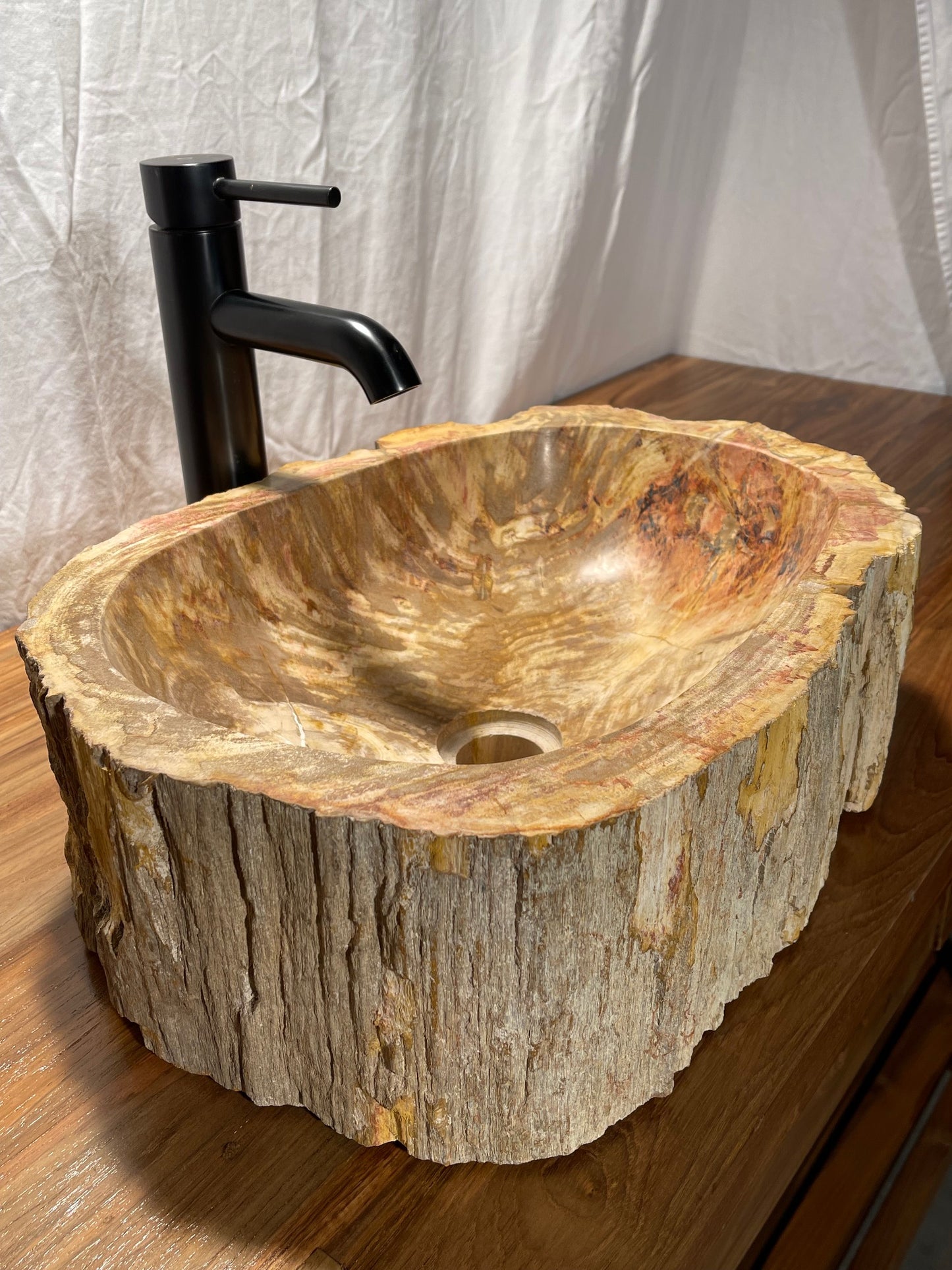 Log shaped petrified wood stone vessel sink with a textured but smooth brown exterior color at impact imports of Boise, Idaho