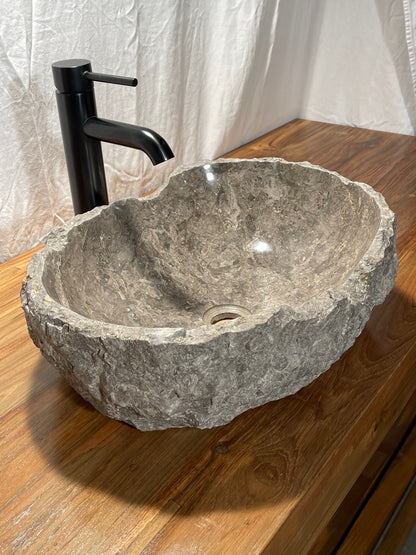Gray marble vessel sink with naturally organic bowl lip and chiseled exterior at Impact Imports