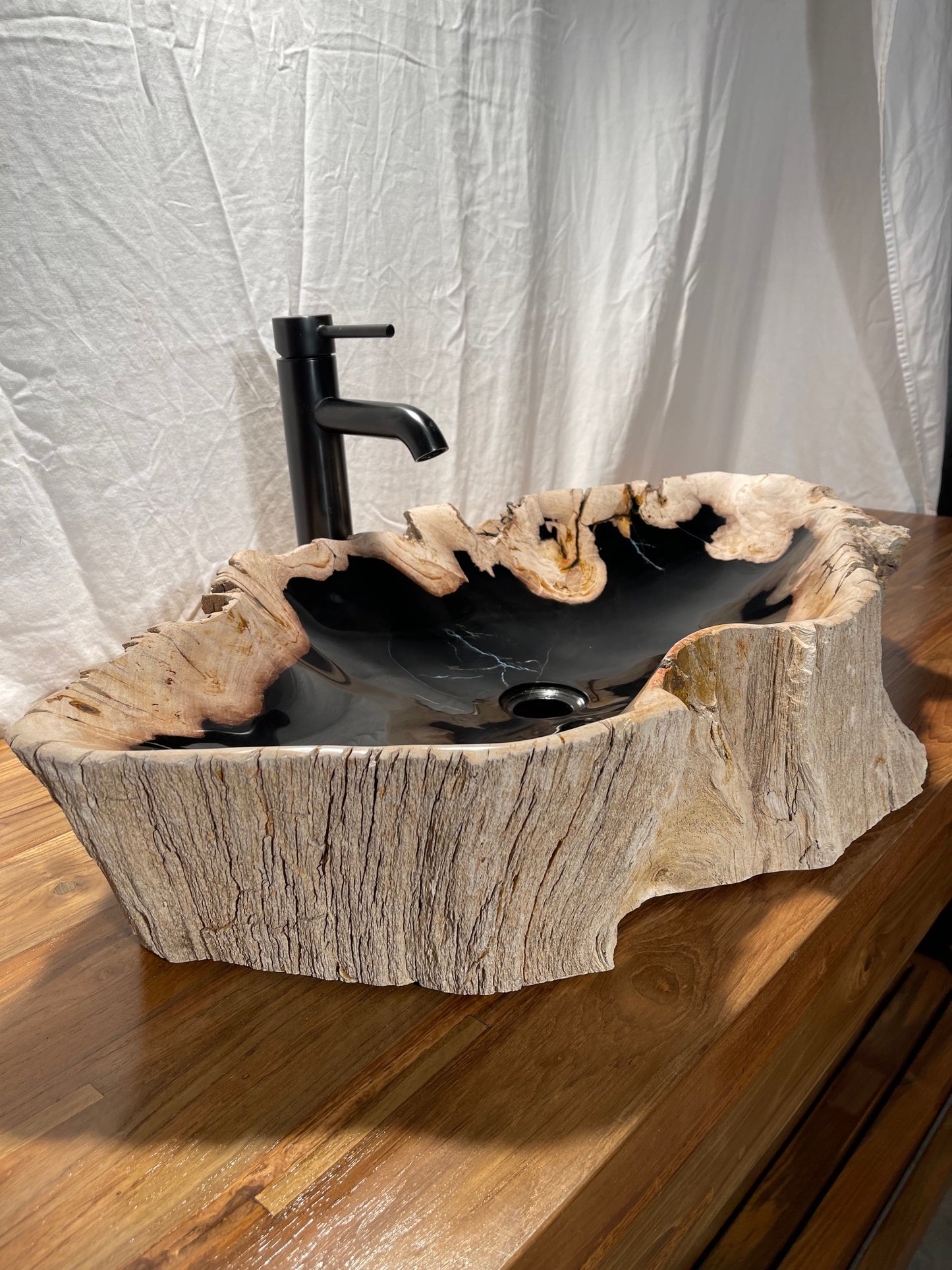 Large petrified wood vessel sink with black and brown colors and a highly polished bowl with natural exterior at Impact Imports in Boise, Idaho