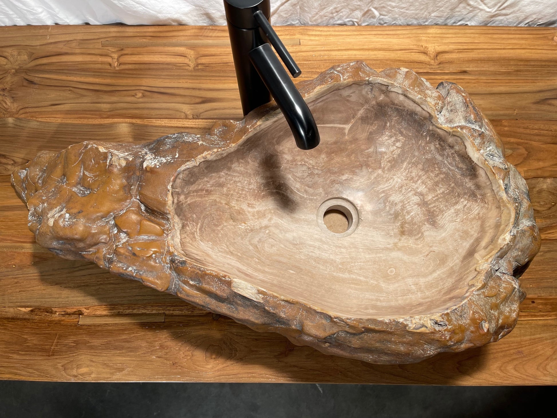 Log shaped petrified wood stone vessel sink with a textured but smooth brown exterior color at impact imports of Boise, Idaho