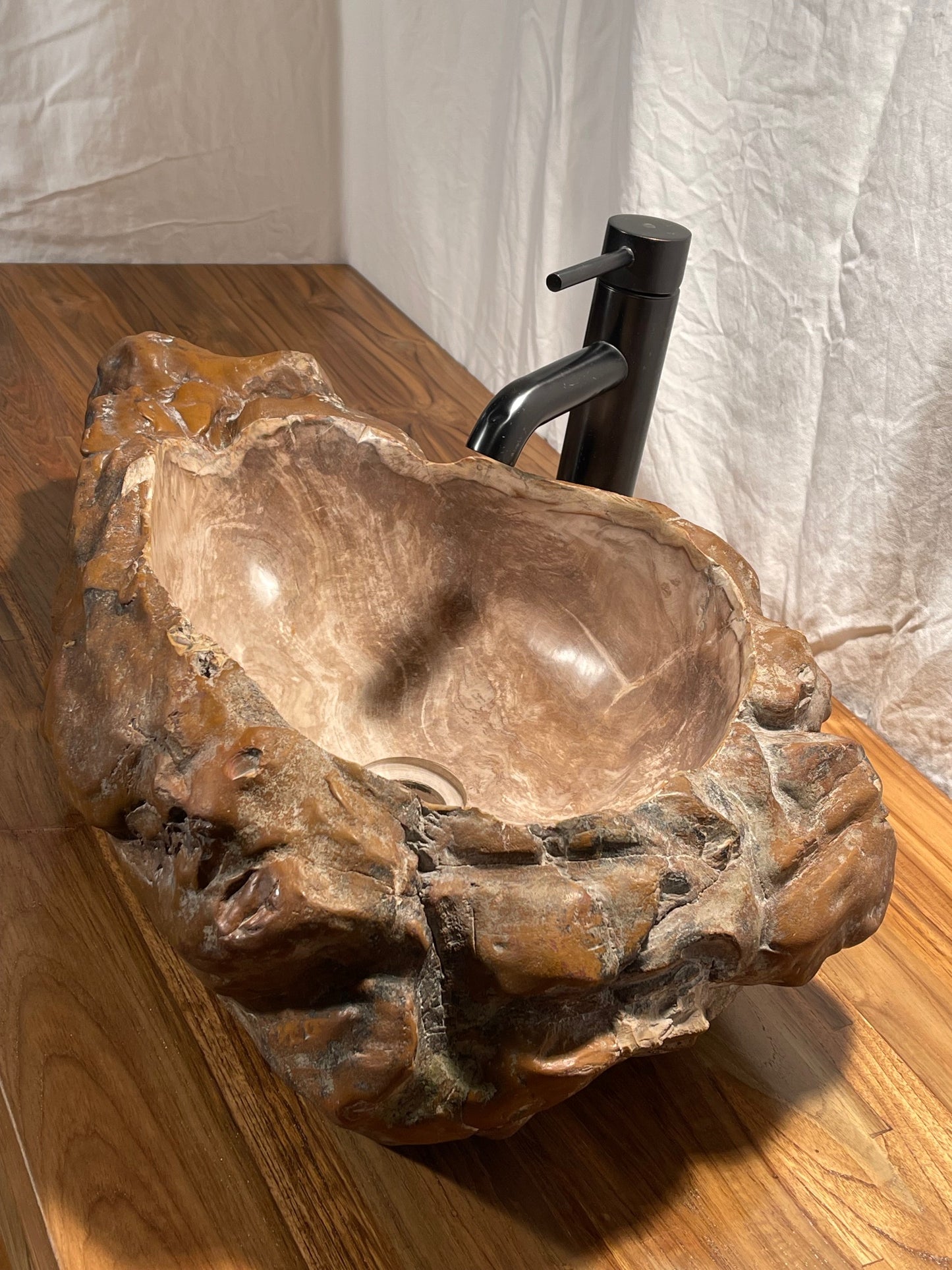 Log shaped petrified wood stone vessel sink with a textured but smooth brown exterior color at impact imports of Boise, Idaho